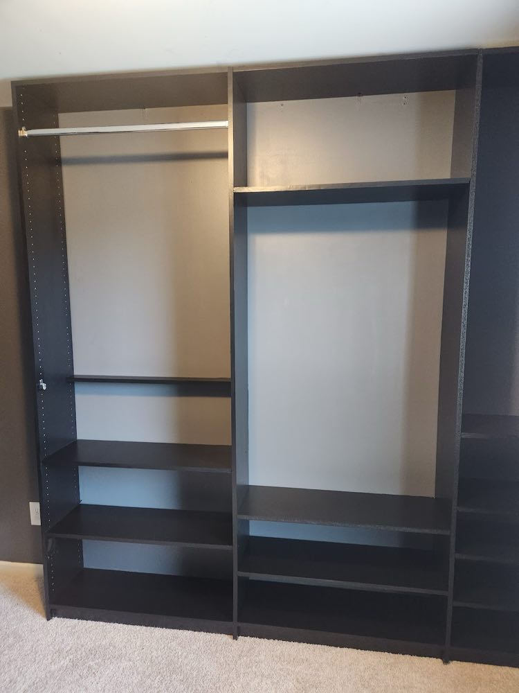 Black closet shelving unit with a hanging rod and open shelves