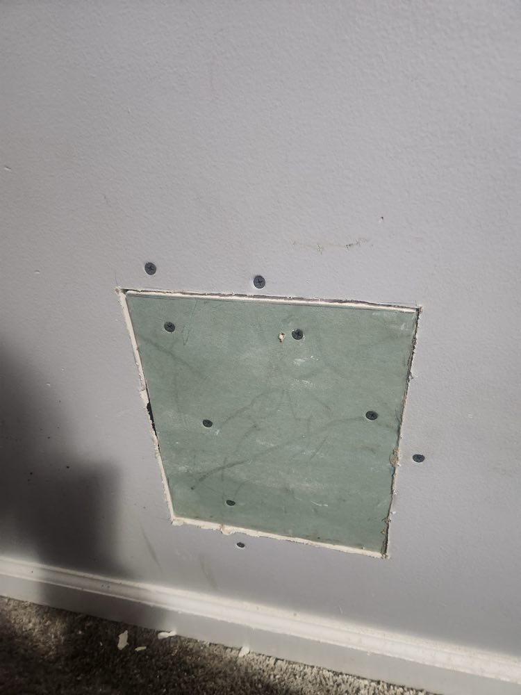 Square drywall patch set into a gray painted wall