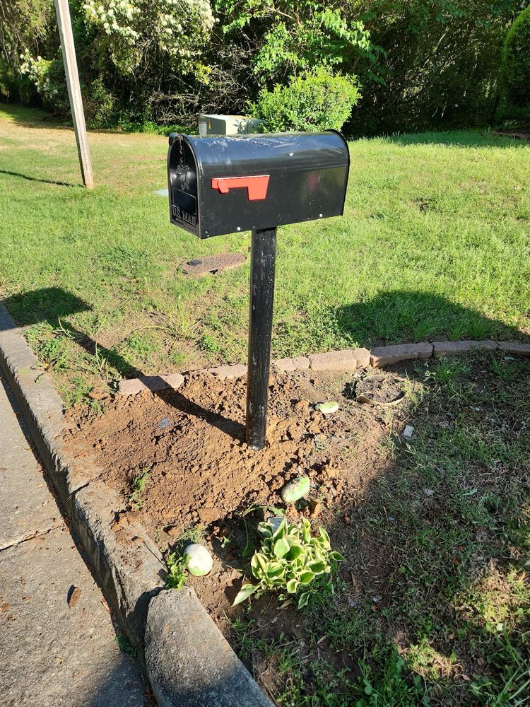 Black mailbox on a post set in fresh soil beside a lawn